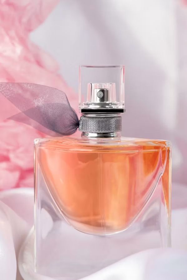 A fragrance bottle photographed on soft pink silk